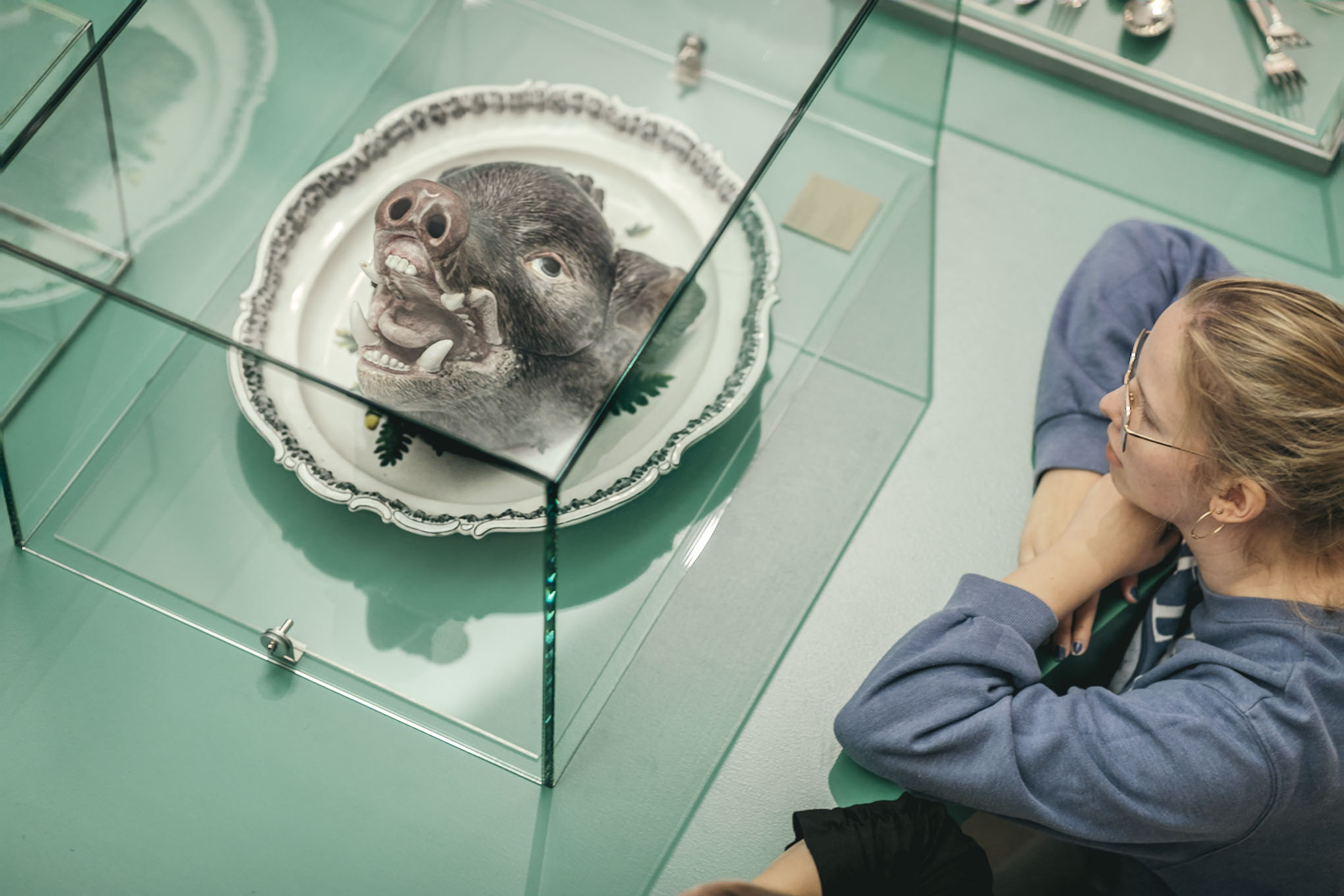 Besucherin betrachtet eine Suppenterrine, die aussieht wie ein Eberkopf