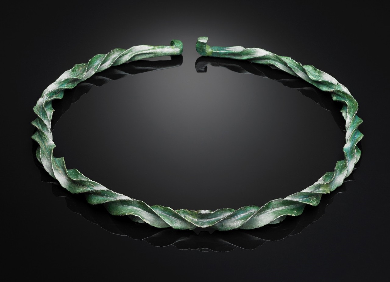Kreisrunder Halsring aus grüner Bronze mit geschwungenem Muster mit scharfer Oberfläche und kleiner Öffnung im Nackenbereich