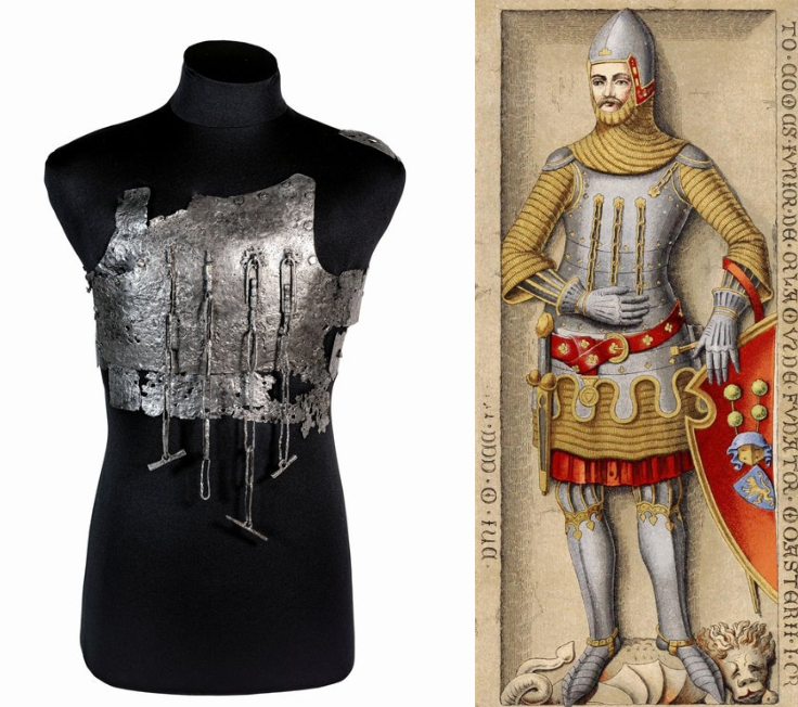 Auf dem Foto sieht man den Oberkörper einer Schaufensterpuppe. Der Oberkörper trägt einen leicht kaputten Metallenen Brustpanzer. Die Zeichnung zeigt einen Ritter mit einem Helm, einer Rüstung, einem Schwert am Gürtel und mit einem Schild. Der Schild hat an der rechten oberen Ecke eine Einbuchtung. Der Ritter steht auf einem besiegten Löwen.