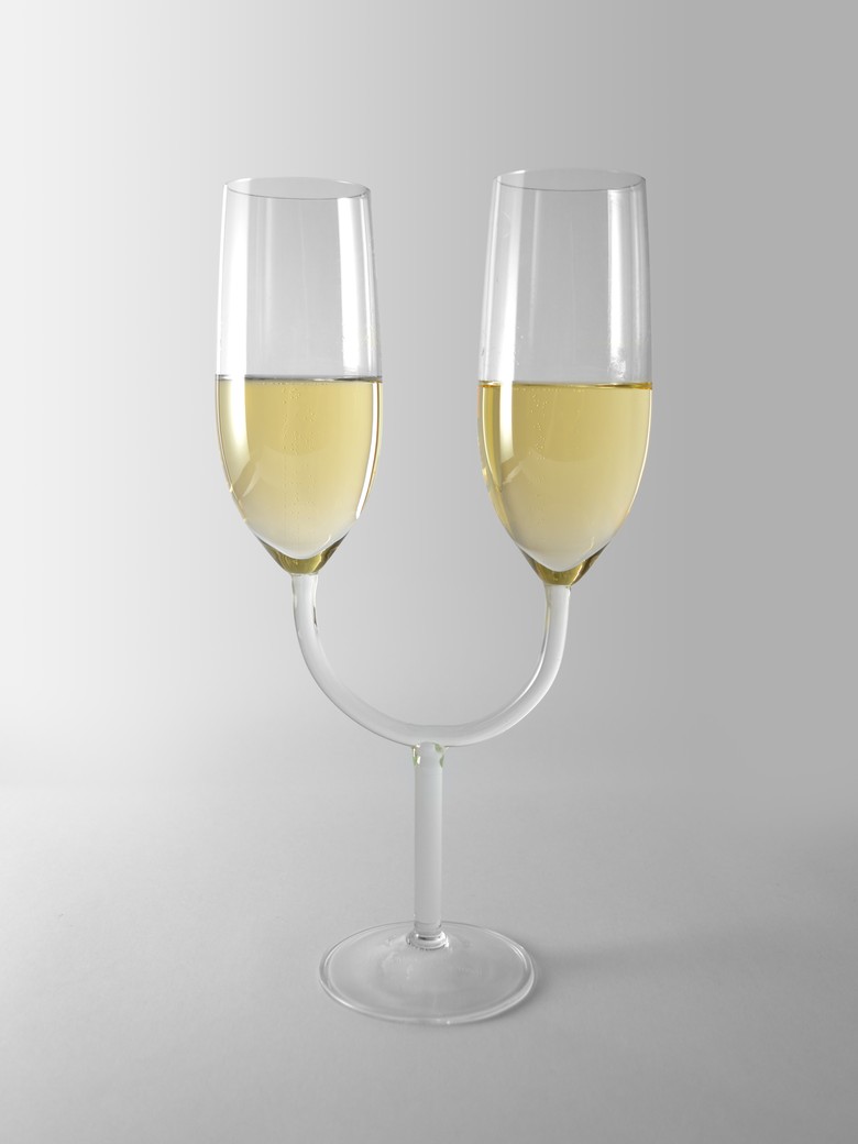 Ein Bild, das ein Weinglas enthält, welches am Stiel verbunden ist. Innerhalb der zwei Gläser befindet sich champagner. Dies nennt sich "The Uncomfortable Champagne Glasses".