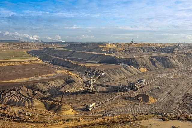 Der Braunkohletagebau Garzweiler, zu sehen ist eine große Fläche mit Baggern und viel freigebauter Kohle und Erde.