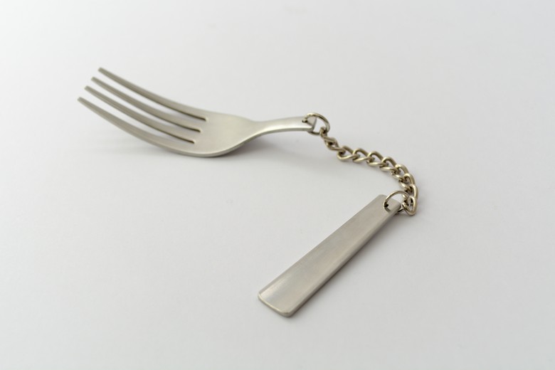 In diesem Bild sieht man eine Gabel, die mithilfe von einer Metallkette zusammengesetzt ist. Diese Gabel nennt sich "The Uncomfortable Fork", ein weiteres Stück aus der Reihe "The Uncomfortable"