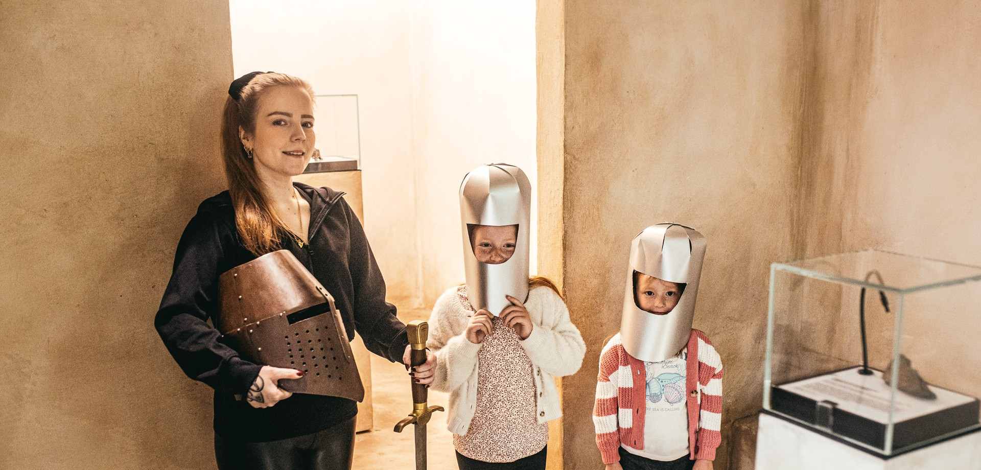 Zwei stolze Kinder mit Ritterhelm. Daneben steht die Guide, die noch das Schwert vom Ritterschlag hält.