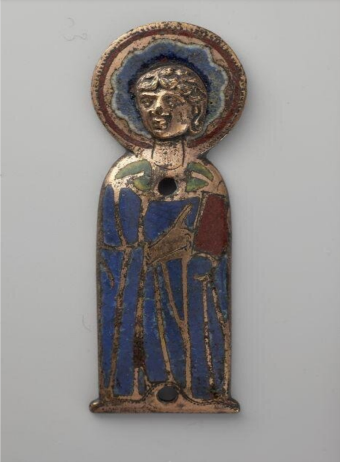 Kleine Figur des Apostels Johannes. Die Figur ist mit Emaille verziert und trägt einen blauen Umhang. Die Schultern, möglicherweise das angedeutete Untergewand, sind grün. In der linken Hand hält die Figur ein rotes Buch.  Der Zeigefinger der rechten Hand ist ausgestreckt und scheint auf das Buch zu verweisen. Die Figur verfügt über einen mit blauer Emaille verzierten Heiligenschein. Auch diese Figur verfügt über zwei Löcher, jeweils eines im Brust- und eines im Fußbereich. Alle abgebildeten Figuren dienten ursprünglich als Beschläge für Vortrage- oder Prozessionskreuze oder liturgische Bücher.