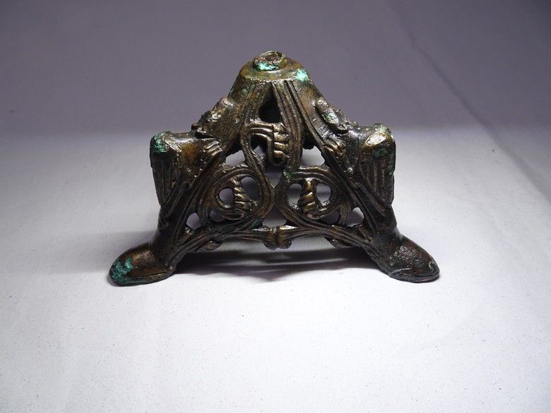 Auf dem Bild ist der bronzefarbende Leuchterfuß mit den Drachen und dem Muster in den Zwischenräumen zusehen.