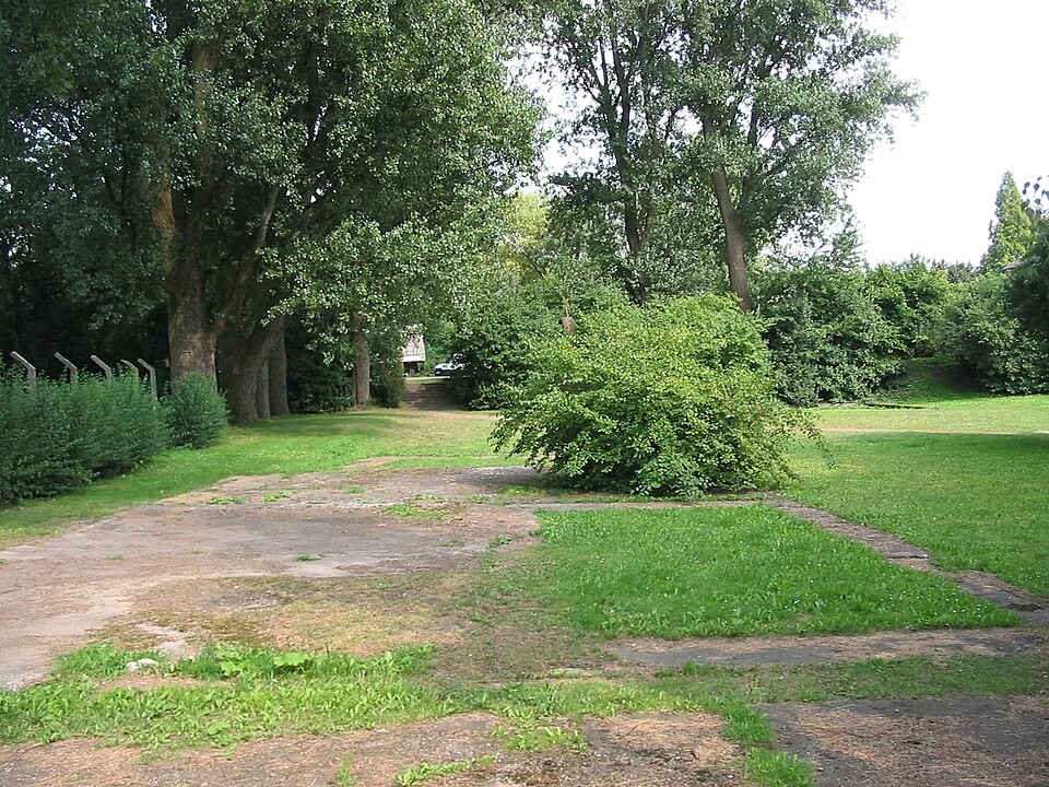 Foto des ehemaligen KZ Buchenwald Außenlager Witten-Annen. Man sieht  eine Wiese mit Spuren eines ehemaligen Gebäude und Überreste eines Zaunes.