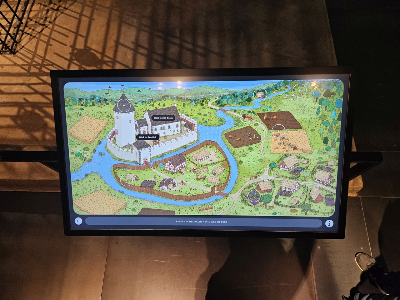 Ein Touchscreen, auf dem die Illustration einer mittelalterlichen Burganlage zu sehen ist.