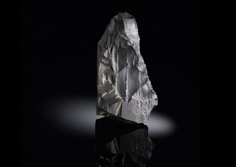 Keilmesser aus Stein, grob dreieckige Form, hellgraue Farbe.