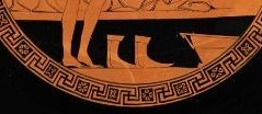 Zu sehen ist ein Bildausschnitt des Bodens der Innenseite der Kylix. Gezeigt werden die nackten Füße eines Teilnehmers. Rechts von ihm steht ein Paar Schuhe. Rechts von den Schuhen findet sich eine Schüssel.