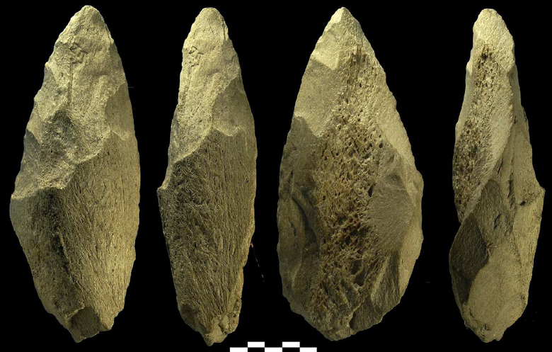 Eine Rundumansicht eines der Knochenfaustkeile aus Italien. Der Faustkeil ist insgesamt länglich und läuft spitz zu. Die Bruchkante von Unter- zu Oberseite ist klar zu erkennen, die obere Seite liegt tiefer. Auch hier sind Spitze und Kanten bearbeitet.