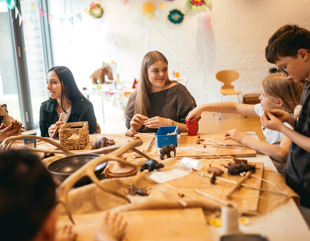 Ferienkinder sitzen gemeinsam beim Basteln